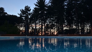 A swimming pool with reflections of trees and a sunset in the background. - Agriturismo Le Case di San Vivaldo (Montaione)