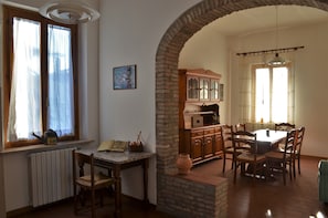 A dining area with a brick archway, wooden dining table, chairs, and a cabinet with glass doors. - Agriturismo Le Case di San Vivaldo (Montaione)