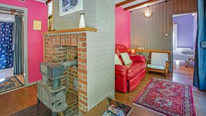 Ein Wohnzimmer mit Kamin aus Backstein, einem roten Ledersofa und einer Holzbalkendecke.