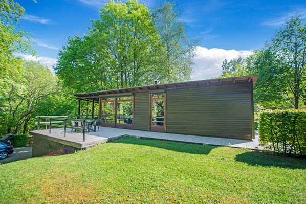 A modern building with a covered patio, a concrete deck, and a grassy area.