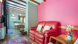 Ein gemütliches Wohnzimmer mit einem roten Ledersofa, einem Holztisch und einem gemusterten Teppich.