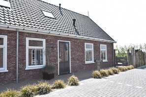 A brick house with a tiled roof, a front door, and two windows.