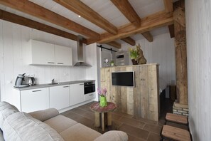 A modern kitchen with white cabinets, a wooden island, and a flat-screen TV.