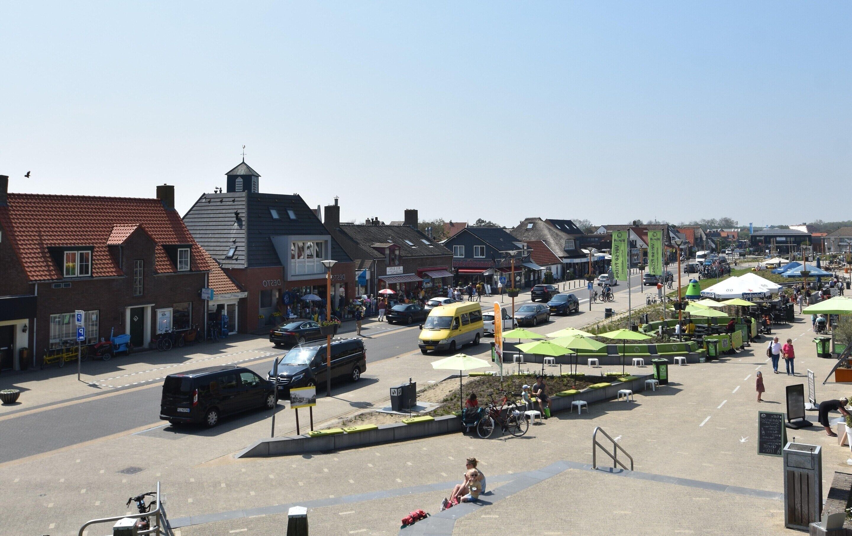 A town square with shops, outdoor seating, and a bike lane.