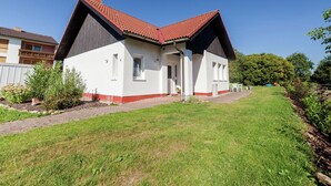 Yhden kerroksen talo, jossa on punatiilinen katto, valkoiset ulkoseinät ja pieni kuisti.