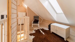 A small, sloped ceiling room with a skylight, wooden furniture, and a cowhide rug. - Apartment in St. Georgen (Bruck an der Grossglocknerstrasse)