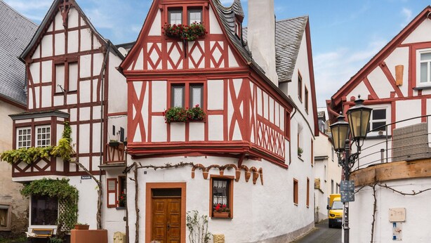 A traditional half-timbered house with a wooden door, windows with flower boxes, and a cobblestone street. - Home for 5 Persons in 1350 Year Old Mosel Town (Ediger-Eller)