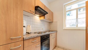 A kitchen with wooden cabinets, a stove, and a window. - Home for 5 Persons in 1350 Year Old Mosel Town (Ediger-Eller)