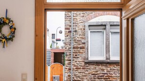 A doorway leading to a courtyard with a stone wall, a wooden gate, and a window with shutters. - Home for 5 Persons in 1350 Year Old Mosel Town (Ediger-Eller)