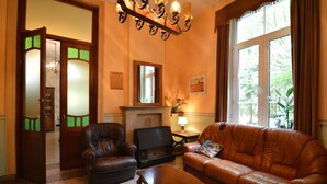 Un soggiorno con divano in pelle, poltrona in pelle, tavolino in legno, camino e una grande finestra con tende.