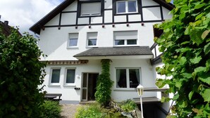 A two-story building with a traditional design, featuring a prominent entrance and a small garden area. - Geraumige Ferienwohnung im Sauerland (Olsberg)
