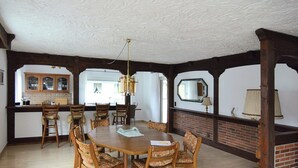 A dining room with a large wooden table, six chairs, a chandelier, and a brick fireplace. - Geraumige Ferienwohnung im Sauerland (Olsberg)