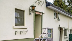 Een gebouw met een groene deur, een raam en een trap die naar de ingang leidt.