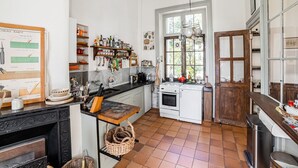 A kitchen with a tiled floor, a stove, a sink, and various kitchen utensils. - Former Train Station With Private Heated Swimming Pool & Fantastic Garden (Liglet)