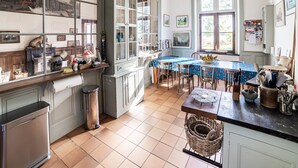 A spacious kitchen with a large dining table, ample counter space, and a view of the garden through the windows. - Former Train Station With Private Heated Swimming Pool & Fantastic Garden (Liglet)
