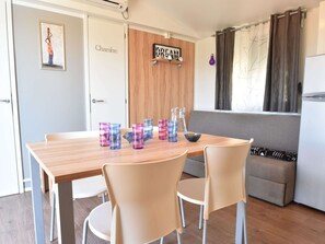 Een kleine keuken met een houten tafel, beige stoelen en een koelkast.