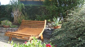 A wooden bench in a garden with potted plants and flowers.