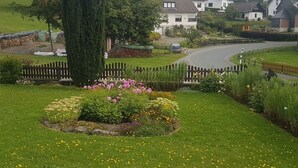A residential area with houses, a winding road, and a well-maintained garden with flowers and a tree.