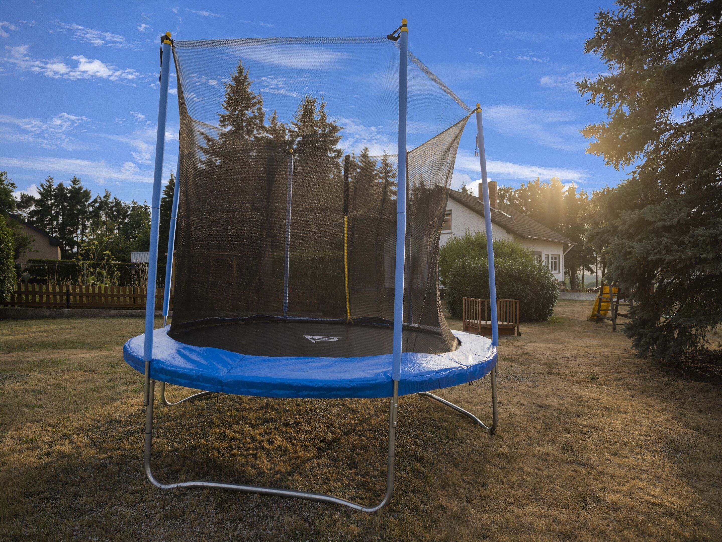 Een trampoline met veiligheidsnet in een achtertuin.