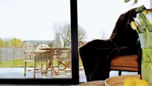Un salon moderne avec un canapé, une table entourée de chaises, un vase rempli de fleurs et un saladier de citrons.