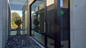 Un bâtiment moderne doté de grandes portes vitrées et offrant une vue sur un jardin comprenant un jardin de rochers et une fontaine.