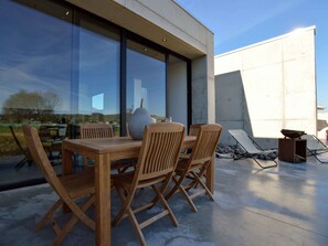 Relax on the patio with a view of the surrounding landscape, surrounded by a wooden table and chairs.