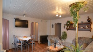 Un salon chaleureux avec une table à manger, des chaises, un canapé et un téléviseur fixé au mur.