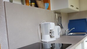 Une cuisine moderne dotée d’un plan de travail noir, d’une machine à café, d’une bouilloire et d’un évier.