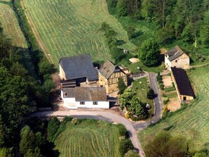 Vista aérea de una propiedad rural con varias construcciones, campos en terrazas y un camino sinuoso.