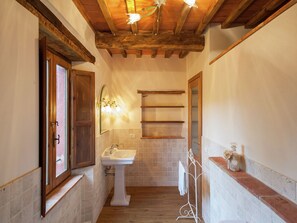 A narrow hallway with a wooden ceiling, a white pedestal sink, and a mirror with wall-mounted shelves. - Castiglione di Garfagnana Haven (Castiglione di Garfagnana)