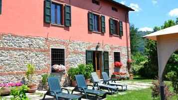 Guests can enjoy a patio with lounge chairs and a table amidst lush greenery.