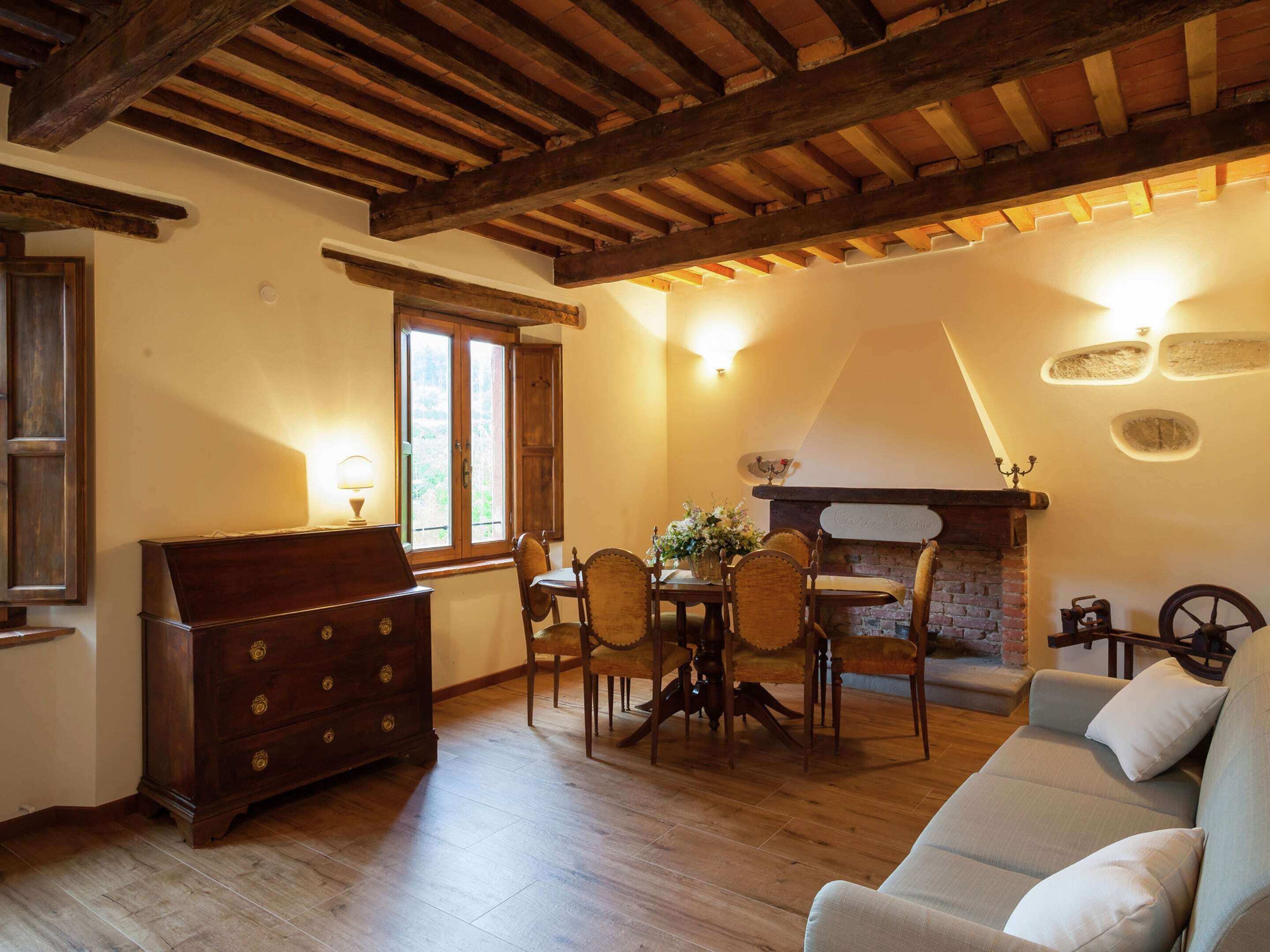 A cozy living room with wooden floors, a fireplace, a sofa, and a dining table with chairs.