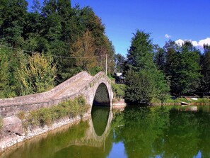 A stone bridge over a calm river, surrounded by dense greenery and trees. - Castiglione di Garfagnana Haven (Castiglione di Garfagnana)