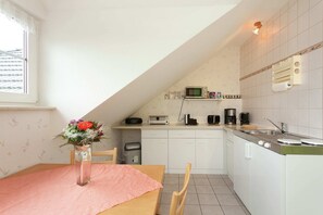 A kitchen with a dining table, chairs, a microwave, a coffee maker, and a sink.