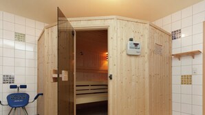 Un cuarto de sauna con puerta de madera, un panel de control y una silla azul que dice "SWING MAXX deluxe".