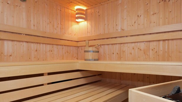 Una sauna de madera con bancos y una piedra para lavarse.