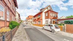 A residential street with traditional European architecture, a parked car, and a clear sky.