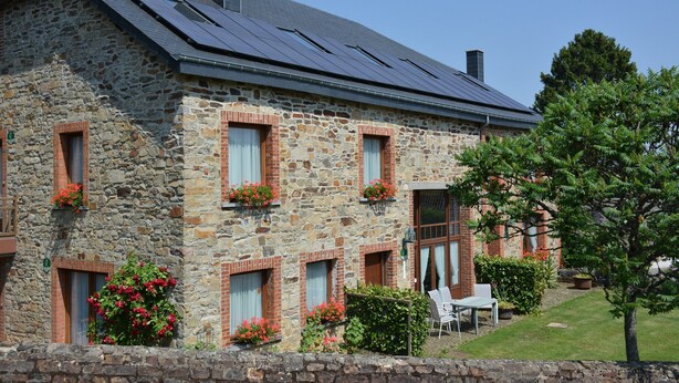 A stone building with solar panels, windows with shutters, and a small garden with chairs. - Spacious Retreat, Daverdisse (Daverdisse)