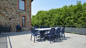 An outdoor patio with a stone building, a table with chairs, and a metal fence. - Spacious Retreat, Daverdisse (Daverdisse)