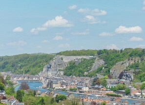 A coastal town with a prominent fort on a hill, a river in the foreground, and a mix of residential and commercial buildings.