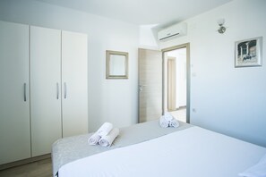 A hotel room with a bed, a wardrobe, a mirror, and an air conditioning unit.