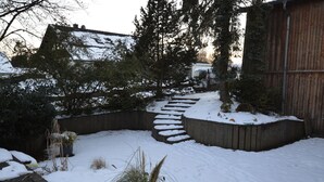 A snow-covered outdoor area with a wooden deck, a stone staircase, and a wooden fence. - Apartment Manderscheid Near Castle Ruins (Manderscheid)