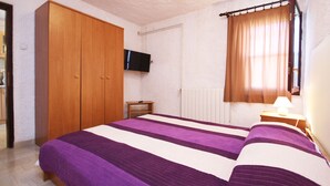 A bedroom with a bed, wooden wardrobe, a television, a window with curtains, and a bedside table with a lamp. - Holiday Apartment Medulin 1 - Elena (Medulin)