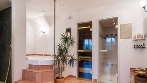 A modern bathroom with a freestanding bathtub, a shower area, and a potted plant.