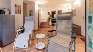 A room with two reclining chairs, a small table, a refrigerator, and a shower area.