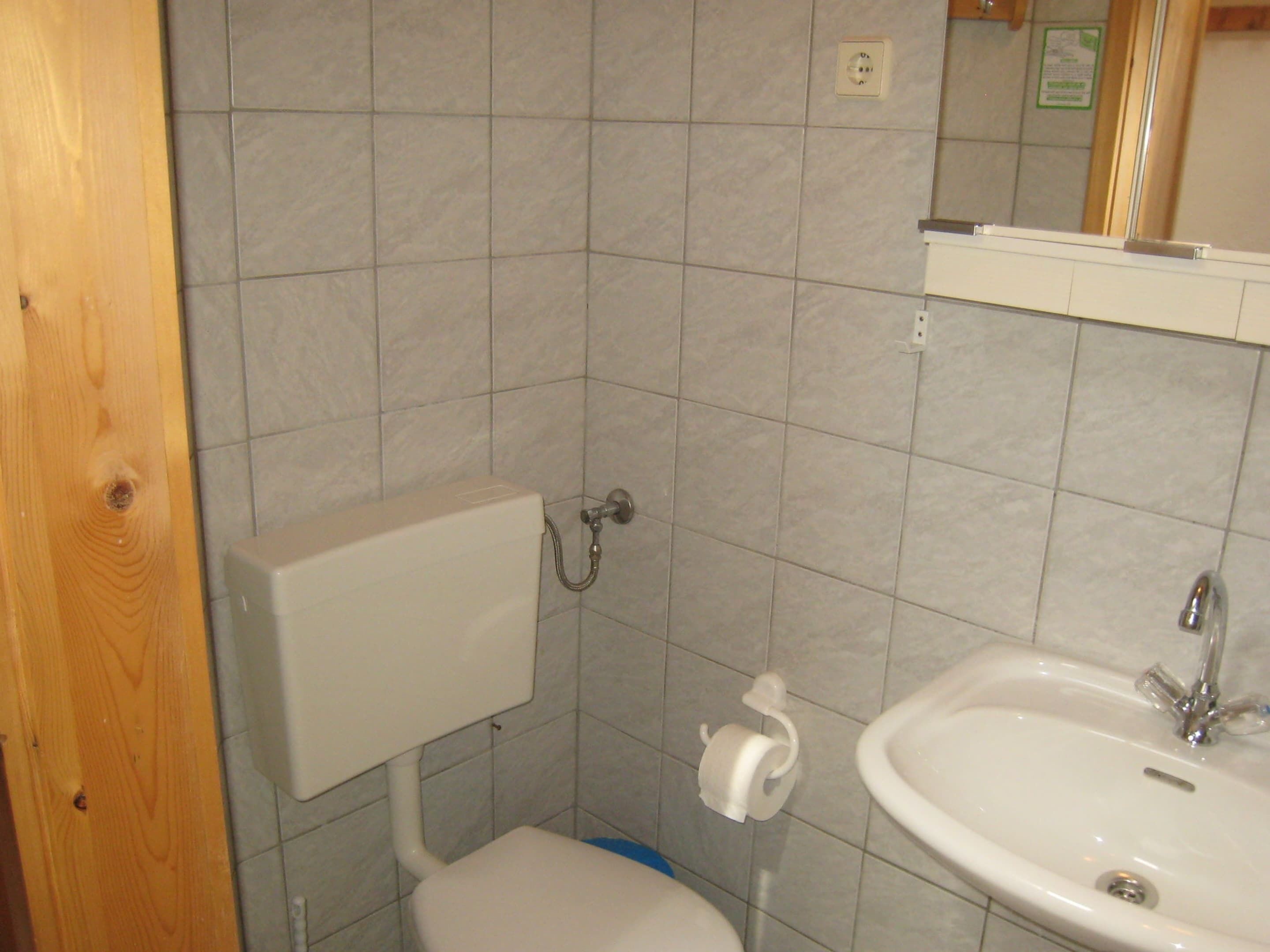 A bathroom with a toilet, sink, and tiled walls.