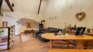 Una sala acogedora con pared de piedra, chimenea, sofá y mesa de comedor de madera.