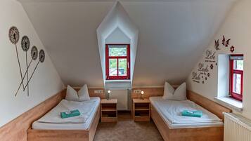 Ein Schlafzimmer mit zwei Betten, einem Fenster, einer Heizung und Wanddekorationen.
