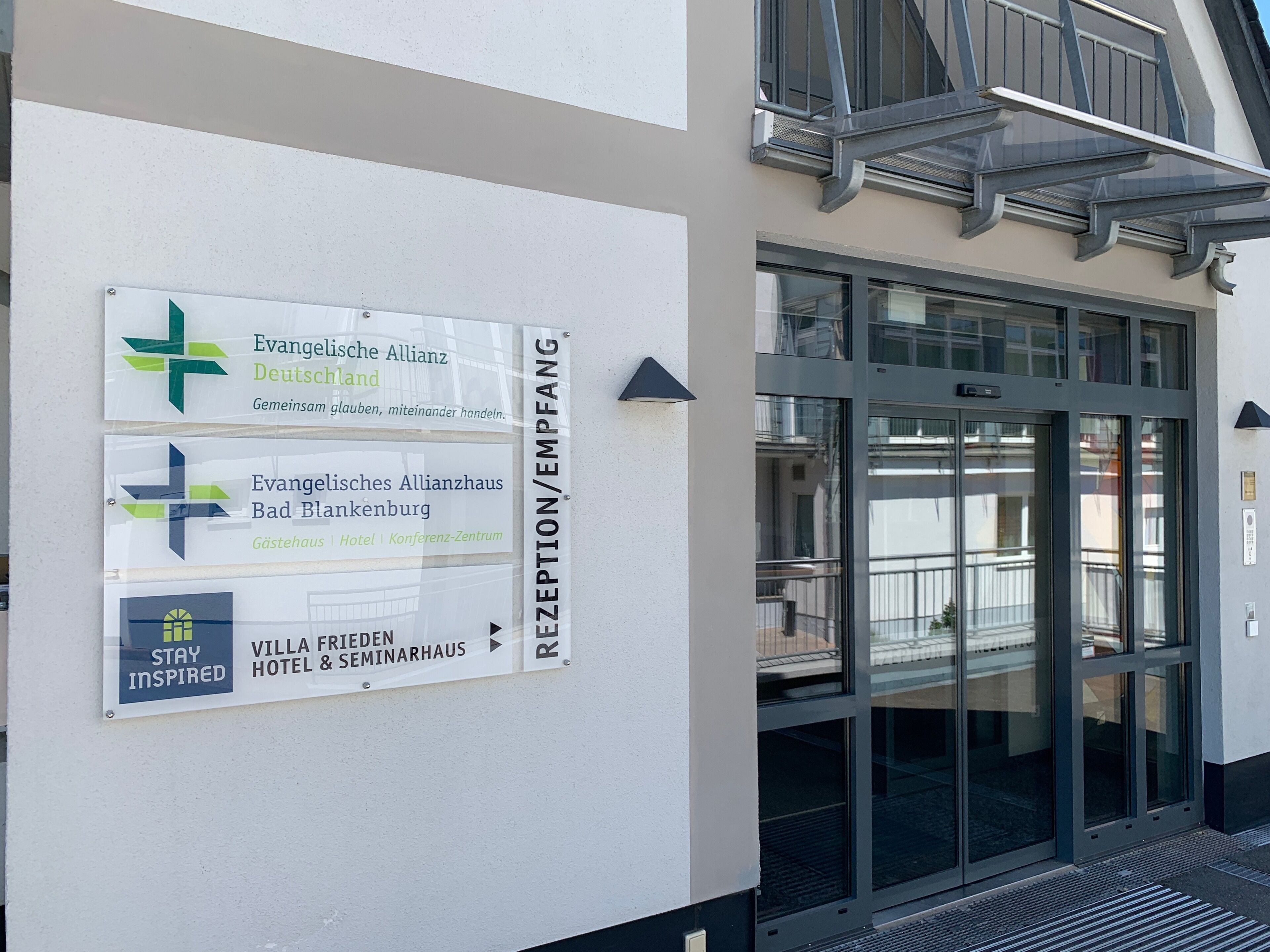 Zona de recepción con señales direccionales para la Evangelische Allianz Deutschland, el Evangelisches Allianzhaus Bad Blankenburg y el Hotel & Seminarios Villa Frieden.