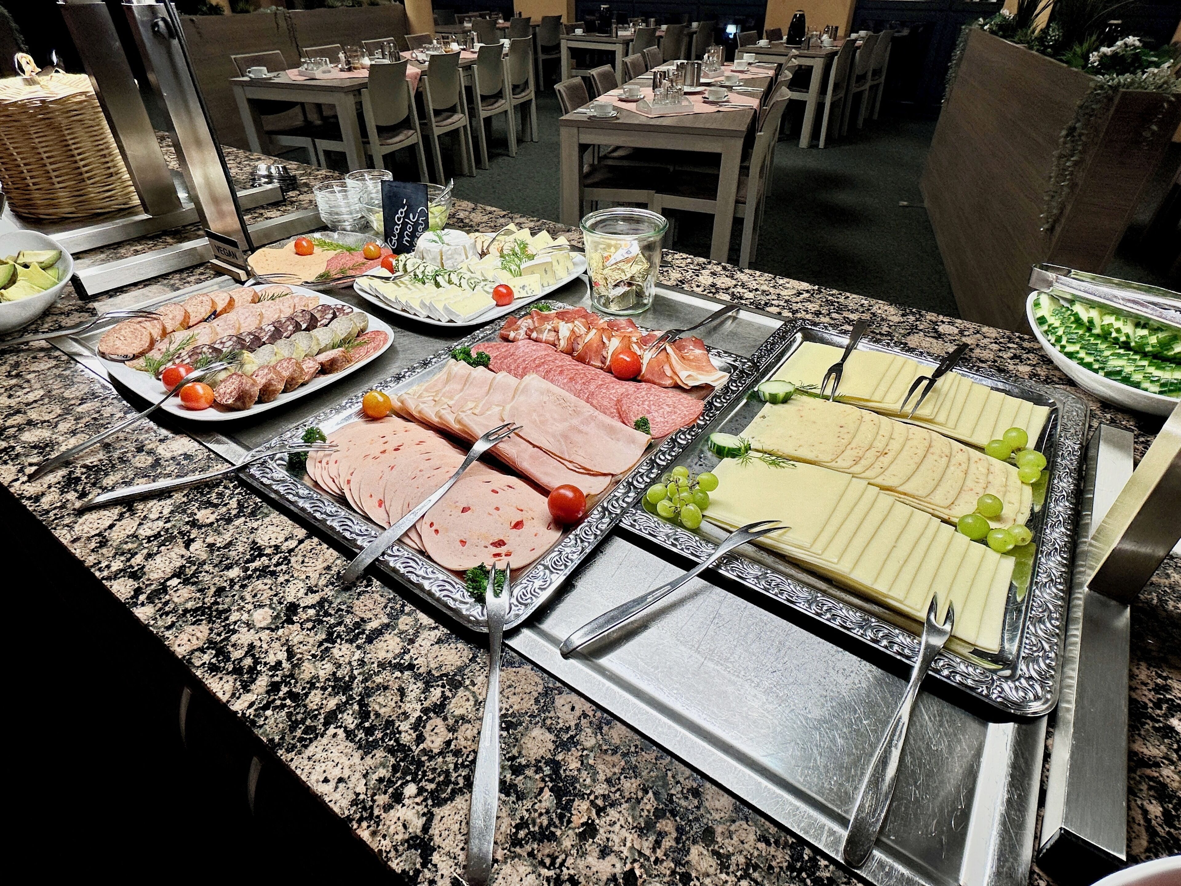 Un bufé con diversas opciones de comida, incluyendo carnes, quesos y verduras.